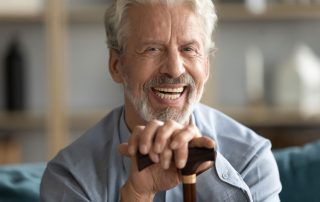 senior smiling with teeth leaning on cane