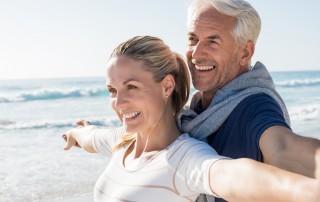 Couple smiling with their arms spread wide, smiling on the beach