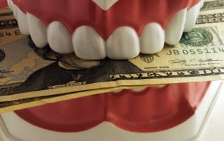 Fake dentures holding a twenty dollar bil because cheap dentures don't deliver good results