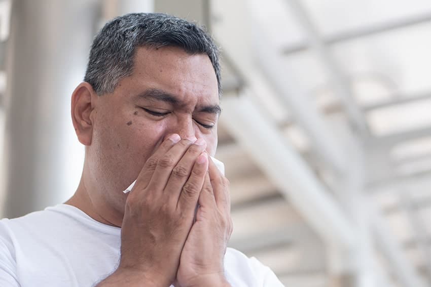 Man sneezing into his hand