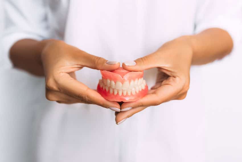 woman holding a set of traditional dentures