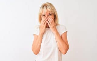 woman covering mouth with hands in embarrassment